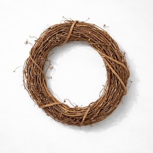 May include: A circular grapevine wreath, featuring intertwined brown branches and twigs. The wreath is tied with a lighter brown band, creating a natural and rustic aesthetic. Ideal for seasonal home decor, the wreath is displayed against a white background.