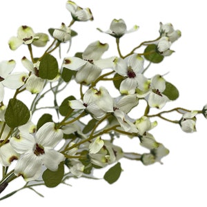 May include: A bouquet of white artificial dogwood flowers with green leaves. The flowers have a delicate, realistic appearance.