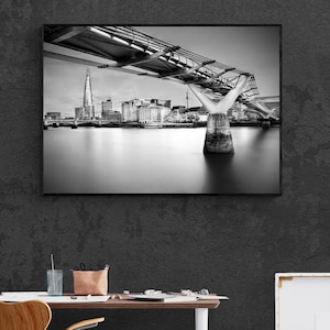 Può includere: Una fotografia in bianco e nero del Millennium Bridge a Londra, in Inghilterra. Il ponte è un ponte pedonale moderno che attraversa il Tamigi. Lo Shard, un grattacielo di Londra, è visibile sullo sfondo.