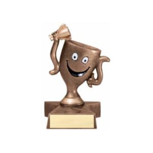 May include: A bronze-colored trophy shaped like a smiling face with a raised arm holding a smaller trophy. The trophy is standing on a star-shaped base with a blank plaque.