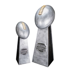 K&ouml;nnte beinhalten: Zwei silberne Fu&szlig;balltroph&auml;en mit schwarzen Sockeln. Die gr&ouml;&szlig;ere Troph&auml;e hat einen silbernen Fu&szlig;ball obenauf und eine schwarz-silberne Plakette mit der Aufschrift "Fantasy Football Champion". Die kleinere Troph&auml;e hat einen silbernen Fu&szlig;ball obenauf und eine schwarz-silberne Plakette mit der Aufschrift "Fantasy Football Champion".