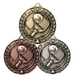 May include: Three gold, bronze, and silver medals with a pickleball paddle and ball design. The medals have a laurel wreath and five stars around the edge.