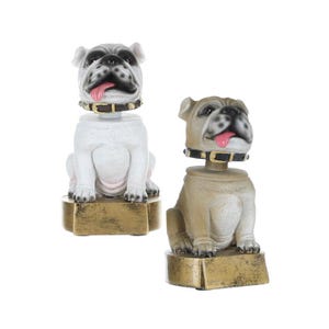 May include: Two bulldog bobblehead figurines. One is white, the other is tan. Both have black collars with gold accents and pink tongues. They sit on gold-colored rectangular bases. The heads are slightly tilted.
