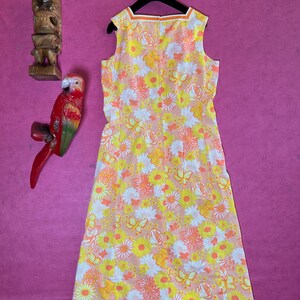 May include: A sleeveless dress with a floral print in shades of pink, yellow, and white. The dress has a scoop neck and a back zip fastening.