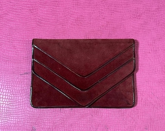 May include: A burgundy suede clutch with a chevron pattern.