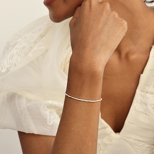 May include: A delicate silver bracelet with tiny beads. The bracelet is simple and elegant, perfect for everyday wear.