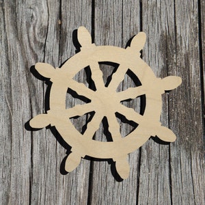 May include: A wooden ship's wheel cutout, painted in a light brown color, with a detailed design of spokes and a central hub. The wheel is against a weathered wooden background.