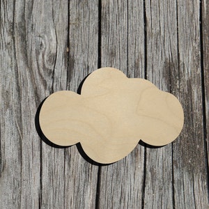 May include: A wooden cutout of a cloud shape, painted in a light brown color. The cloud is on a gray wooden background.