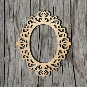 May include: A wooden oval frame with a decorative, intricate design. The frame is made of light brown wood and has a delicate, ornate pattern.