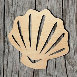 May include: A wooden cutout of a seashell with a detailed design. The seashell is light brown and has a smooth surface.