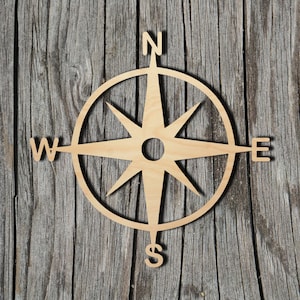 May include: A wooden compass with a starburst design and the letters N, S, E, and W. The compass is on a wood background.