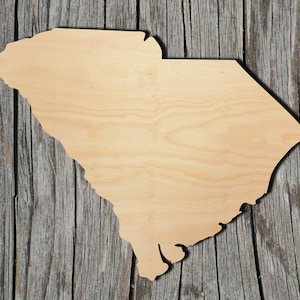 Könnte beinhalten: Ein Holzausschnitt des Bundesstaates South Carolina. Der Ausschnitt ist hellbraun und hat eine glatte, unbehandelte Oberfläche.