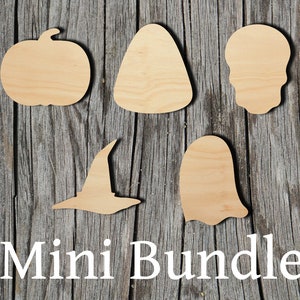 May include: A wooden mini bundle of Halloween-themed cutouts. The set includes a pumpkin, candy corn, skull, witch hat, and ghost. The words "Mini Bundle" are printed in white at the bottom. The cutouts are made of light-colored wood and are arranged on a weathered wooden surface.
