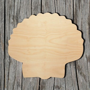 May include: A wooden cutout of a seashell in the shape of a scallop. The cutout is made of light-colored wood and has a smooth, unfinished surface.