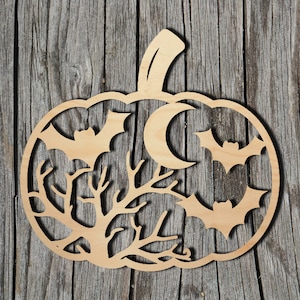 May include: A light brown wooden pumpkin decoration featuring a bat, moon, and tree branch design. The bats and moon are cut out of the pumpkin shape. The background is a wooden surface. The pumpkin has a stem.