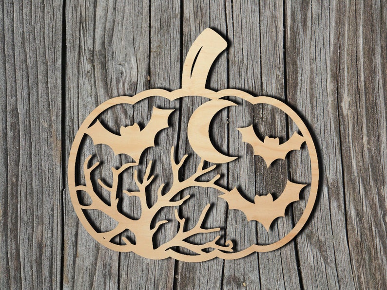 May include: A light brown wooden pumpkin decoration featuring a bat, moon, and tree branch design. The bats and moon are cut out of the pumpkin shape. The background is a wooden surface. The pumpkin has a stem.