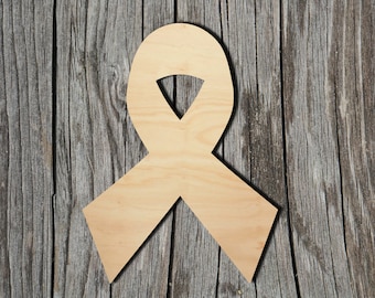 May include: A wooden cutout of a ribbon in the shape of a bow. The ribbon is light brown and is against a wood background.