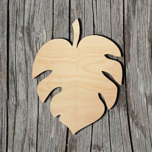 May include: A wooden cutout of a monstera leaf, a tropical plant with large, heart-shaped leaves, against a rustic wood background.