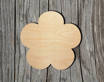 May include: A wooden cutout in the shape of a flower with five petals. The flower is light brown and has a smooth surface. It is sitting on a weathered wooden background.