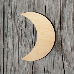 May include: A crescent moon shape cut from light-colored, smooth wood with a visible natural grain pattern. The object features a curved, pointed design and a flat surface, showcasing the light tan color and texture of the unfinished wood material.