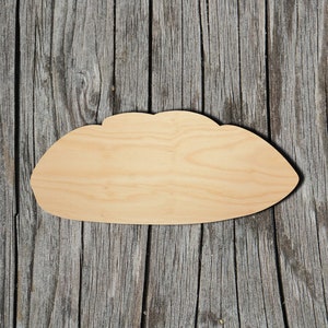 May include: A wooden cutout in the shape of a loaf of bread. The cutout is light brown and has a smooth surface. It is sitting on a wooden background.
