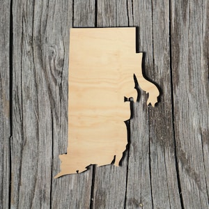 May include: A wooden cutout of the state of Rhode Island. The cutout is light brown and is placed on a weathered gray wooden background.