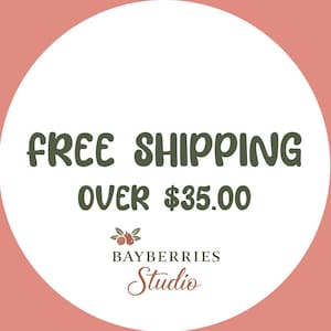 Puede incluir: Un gr&aacute;fico circular con fondo rosa empolvado y centro blanco. El texto dice FREE SHIPPING OVER $35.00 en verde oscuro. Debajo, una peque&ntilde;a ilustraci&oacute;n de bayas con hojas se sit&uacute;a sobre el texto BAYBERRIES STUDIO en color negro.