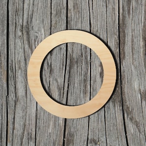 May include: A natural wood circle with a large hole in the center. The circle is on a weathered wood background.