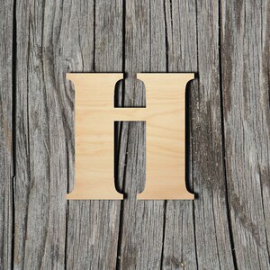 May include: A wooden letter H, painted in a light wood color, is placed on a weathered gray wood background.