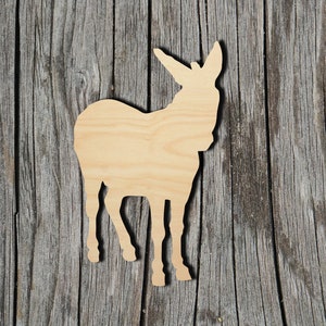 May include: A wooden cutout of a donkey, standing on a gray wooden background. The donkey is facing the right side of the image.