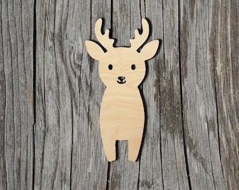 May include: A light-colored wooden cutout in the shape of a deer with antlers, two ears, and a simple facial expression featuring two circular eyes and a small nose, presented as a flat, smooth, and unpainted wooden silhouette.