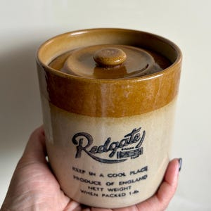 Peut inclure: Un pot en grès vintage avec un couvercle. Le pot est beige avec une bande et un couvercle marron. Le texte "Redgate" est imprimé sur le devant, ainsi que d'autres textes. Le pot pèse 0,45 kg emballé.