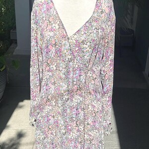 May include: A long-sleeved, floral print dress with a V-neckline and button closure. The dress is made of a lightweight fabric and has a flowy silhouette.