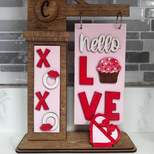 May include: A set of three ceramic mugs with a speckled, cream-colored glaze. Each mug features a different hand-painted floral design in shades of blue, green, and yellow. The mugs have a simple, modern shape.