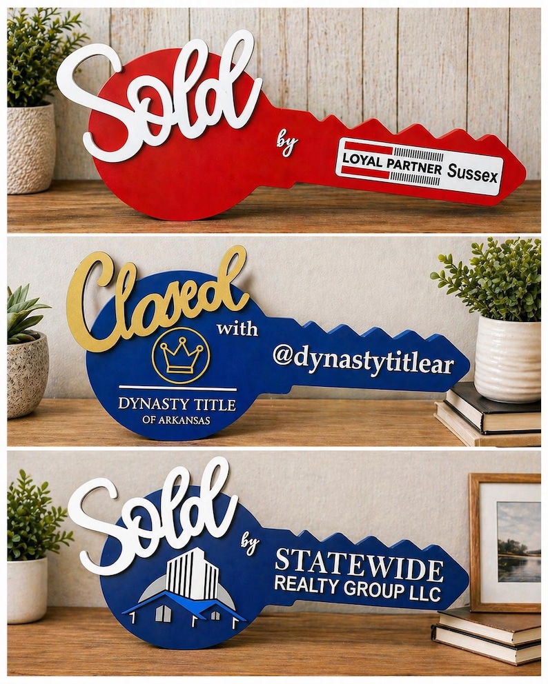 May include: Three decorative wooden key-shaped signs. The first is red with white text reading Sold by LOYAL PARTNER Sussex. The second is blue with gold text reading Closed with @dynastytitlear and DYNASTY TITLE OF ARKANSAS. The third is blue with white text reading Sold by STATEWIDE REALTY GROUP LLC.