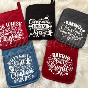 May include: Set of five red, black, gray, blue, and red oven mitts with white text. The text on the mitts reads "We Whisk You a Merry Christmas", "Christmas Baking Queen", "Baking Christmas Memories", "Let's Bake Stuff and Watch Christmas Movies", and "Baking Spirits Bright".
