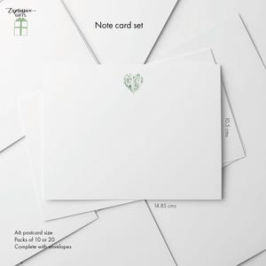 May include: White A6 postcard set with a green heart design. The set includes packs of 10 or 20 cards and envelopes. Each card measures 14.85 cm x 10.5 cm. The words "Expressive GIFTS" and "Note card set" are also visible.