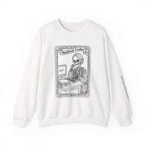 Può includere: Felpa bianca con grafica in bianco e nero di uno scheletro al lavoro su un computer, con la scritta "Medical Coder". La manica riporta la scritta "did you document it?" Un regalo unico per i professionisti medici.