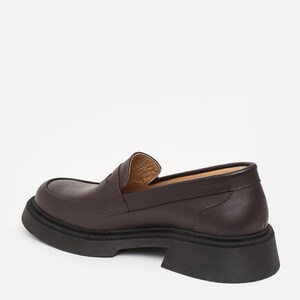 K&ouml;nnte beinhalten: Ein brauner Lederloafer mit dicker schwarzer Sohle. Der Schuh hat eine runde Spitze und ein klassisches Penny-Loafer-Design. Die Sohle ist etwa 5 cm dick.