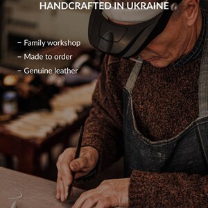 May include: A craftsperson wearing a black head-mounted magnifier works on a piece of genuine leather. Text overlay reads: HANDCRAFTED IN UKRAINE, Family workshop, Made to order, Genuine leather. The artisan wears a brown sweater and denim apron.