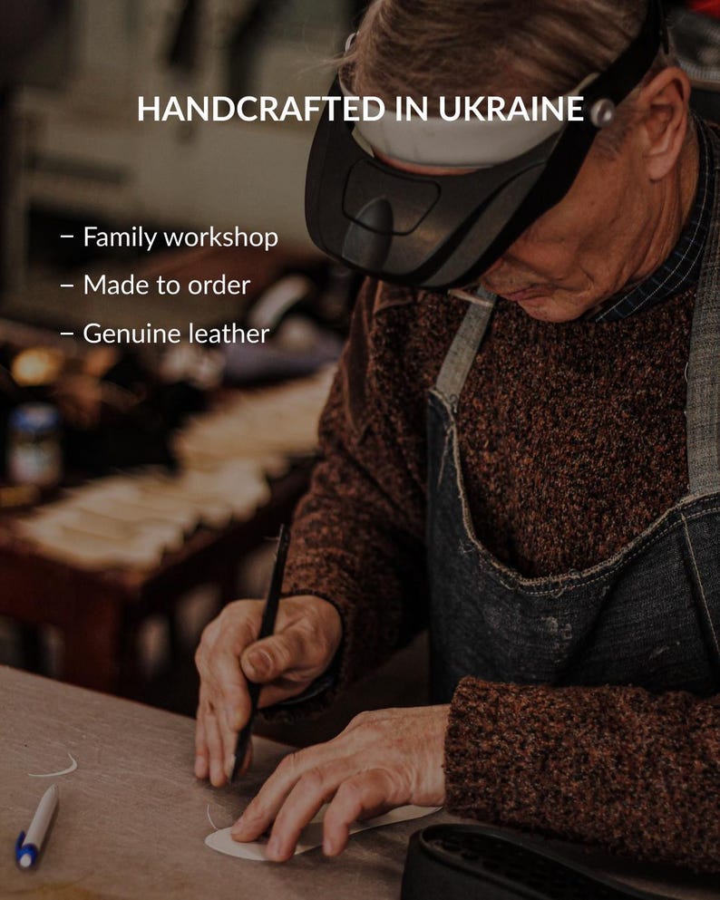 May include: A craftsperson wearing a black head-mounted magnifier works on a piece of genuine leather. Text overlay reads: HANDCRAFTED IN UKRAINE, Family workshop, Made to order, Genuine leather. The artisan wears a brown sweater and denim apron.