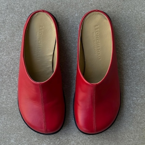 May include: A pair of red leather slip-on shoes with a rounded toe and a black sole. The interior is a light tan color, and the brand name "LEONCHENKO" is visible inside. The shoes are made in Ukraine.