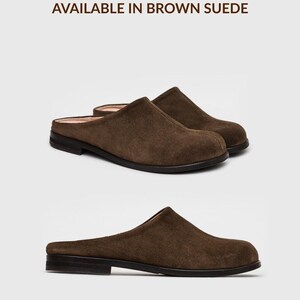 May include: A pair of brown suede mules featuring a closed rounded toe, a low heel, and a slip-on design. The text "AVAILABLE IN BROWN SUEDE" is printed above the shoes, and "*also available in other colours" is printed below the shoes.