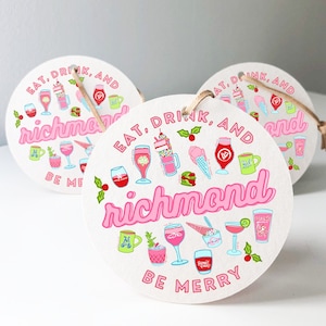 May include: Three round, white, paper ornaments with pink and blue illustrations of drinks and the text "Eat, Drink, and Richmond, Be Merry".