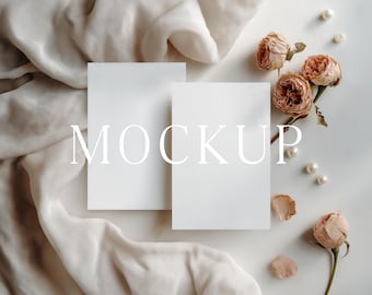 May include: A mockup scene featuring two blank white cards with the word "MOCKUP" overlaid. The cards are surrounded by dried roses, pearls, and a flowing beige fabric, creating an elegant and minimalist aesthetic.