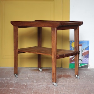 Può includere: Un tavolino in legno scuro a due livelli con piano rettangolare e ripiano inferiore a doghe. Il tavolo ha quattro gambe con piccole rotelle. Il tavolo misura circa 61 cm di lunghezza, 46 cm di larghezza e 71 cm di altezza.