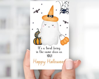 May include: A Halloween-themed gift tag featuring a cartoon ghost wearing a witch hat and holding a pumpkin-shaped treat bag. The tag includes the text "It's a treat being in the same class as YOU!" and "Happy Halloween."