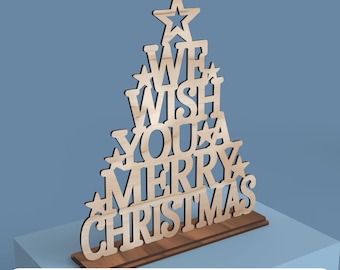 May include: Wooden Christmas tree decoration with the words "We Wish You a Merry Christmas" cut out. The tree is light brown and sits on a darker brown base. Stars are incorporated into the design. The words "DIGITAL FILE FOR LASER CUTTING" are at the bottom.