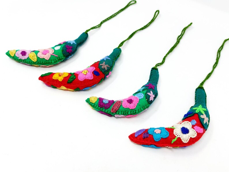 May include: Four handmade green and red felt chili pepper ornaments with colourful embroidered flowers. Each ornament has a green string for hanging.