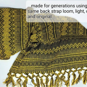 May include: A woven textile featuring a repeating geometric pattern in black and yellow. The fabric includes a fringed edge with twisted tassels. Text overlay reads: ...made for generations using the same back strap loom, light, cozy and original...